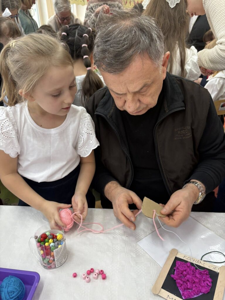 dziewczynka siedzi z dziadkiem przy stoliku 