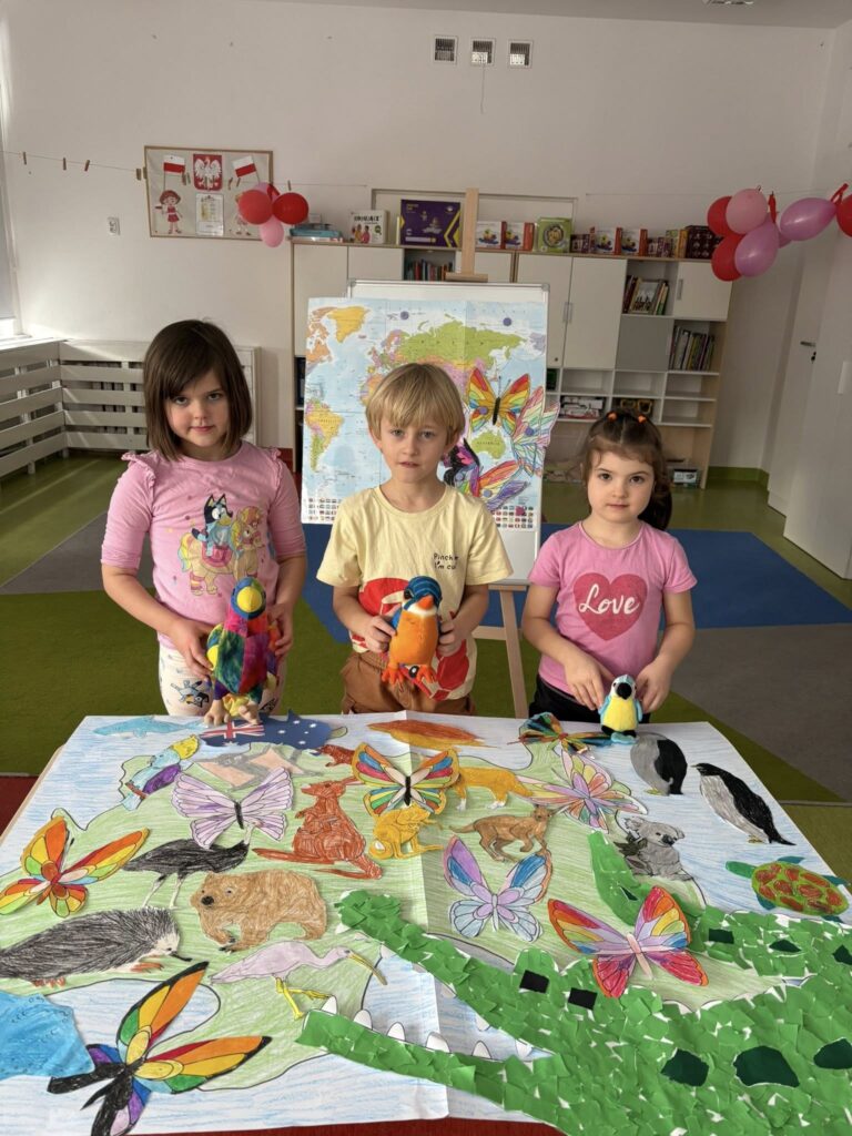 dzieci stoją przy stoliku z pluszakami