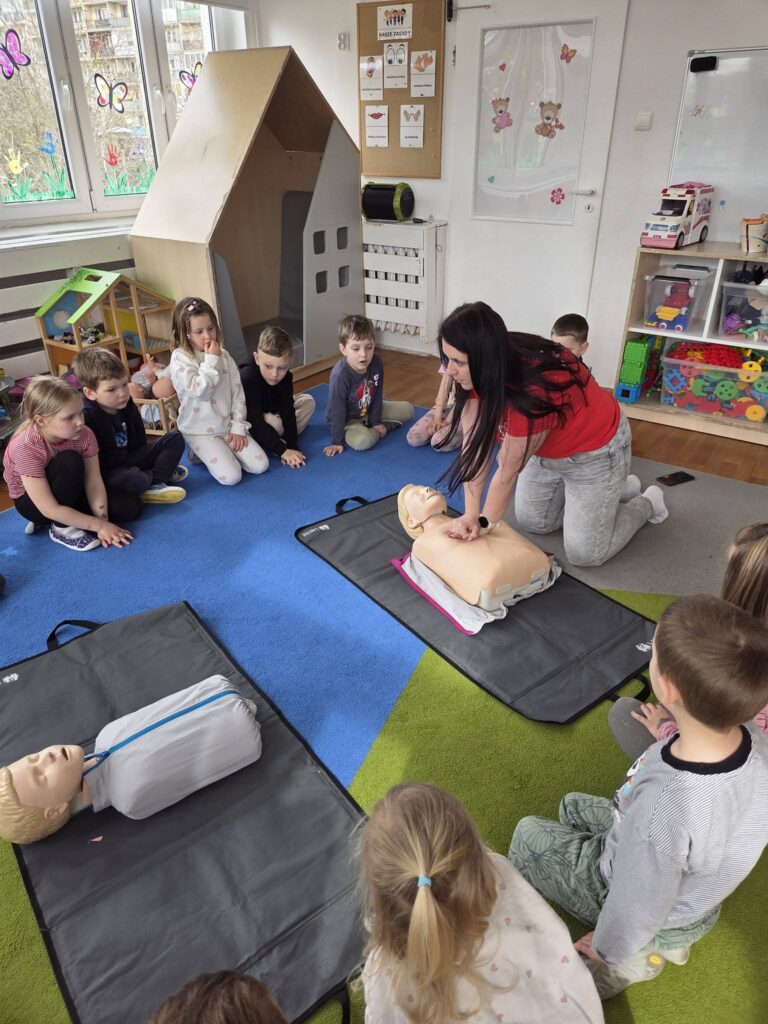 zajęcia pokazowe z pierwszej pomocy, Pani prezentuje uciski na manekinie  