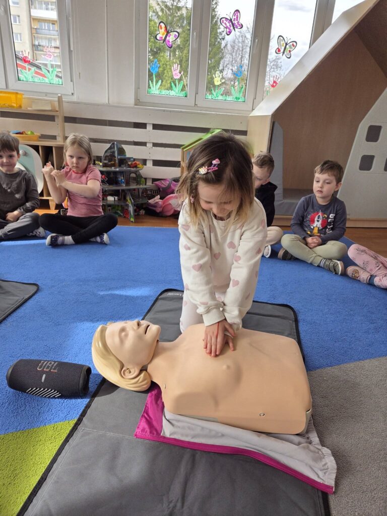 zajęcia pokazowe z pierwszej pomocy , dziewczynka ćwiczy na manekinie uciski 